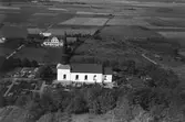 Flygfoto över Söndrums kyrka och kyrkogård med odlingslandskapet i bakgrunden.