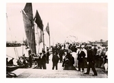 Hamnpiren i Varberg 1905, full av folk och segelskutor. Till höger i bild syns varm- och kallbadhusen.