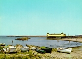 Kallbadhuset och Barnens badstrand i Varberg med båtar uppdragna på stranden.