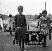 Flickor bär på kransar till midsommarstång i Brevens bruk, 1960-tal
