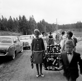 Flickor bär kransar till midsommarstången i Brevens bruk, 1960-tal