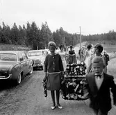 Flickor bär kransar till midsommarstången i Brevens bruk, 1960-tal