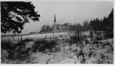 Hovsta kyrka på andra sidan av snöfylld åker, 1940-tal