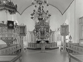 Interiörbild från Rolfstorps kyrka av koret med korbänkar på sidorna och sakristian bakom skranket. Altare, altarring, dopfunt, predikstol.