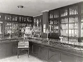 Interiör av John Viktorins guldsmedsaffär, som låg vid hörnet Kungsgatan-Norrgatan, kvarteret Berget, Varberg. Butiksdiskar och skyltskåp.