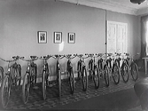 Cyklar från Monark uppställda prydligt längs en vägg inne i ett möblerat rum.