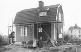 Familj framför hus i Hjärsta, 1910-tal