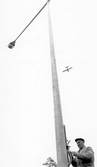 Linjemontör monterar i belysningsmast, 1950-tal