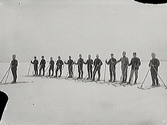 Skidande militärer står uppställda på rad i snön, troligen ute på hav eller sjö då sikten är vid. (Negativet har två skador)