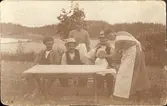 Familj vid trädgårdsbord, ca 1900