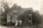 Familj framför hus i Ekeby-Almby, ca 1900
