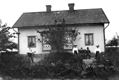 Familj framför hus, 1910 ca