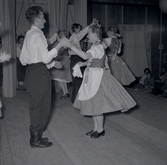 Bild tagen i samband med att flyktingar ifrån Ungern kom 1956.  Män och kvinnor som dansar. Kvinnorna dansar i traditionella romska folkträkter i Godtemplargården hösten 56 - våren 57.