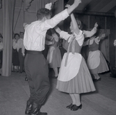Bild tagen i samband med att flyktingar ifrån Ungern kom 1956.  Män och kvinnor som dansar. Kvinnorna dansar i traditionella romska folkträkter i Godtemplargården hösten 56 - våren 57.