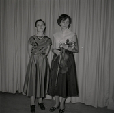 Bild tagen i samband med att flyktingar ifrån Ungern kom 1956.  Två kvinnor som står på scen. Den ena kvinnan håller i ett stråkinstrument i Godtemplargården hösten 56 - våren 57.
