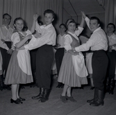 Bild tagen i samband med att flyktingar ifrån Ungern kom 1956. Män och kvinnor som dansar. Kvinnorna dansar i traditionella romska folkträkter i Godtemplargården hösten 56 - våren 57.