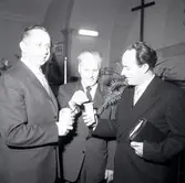 Tre herrar i kostym. Stoppar mynt i en bössa när Filadelfiakyrkan firade 25 år.