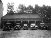 Personbilar uppställda framför garage, 1920-tal