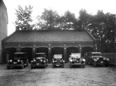 Personbilar uppställda framför garage, 1920-tal