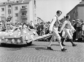 Män i folkdräkt drar blommig vagn på Barnens dag, 1953