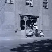 Man som vevar en markis vid ett skylfönser till en sport- och fiskeaffär troligen i Borgholm.