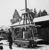 Män vid vagn för transportabel belysningsmast vid sågen i Hjortkvarn, 1950-tal