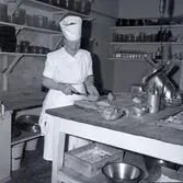 En kvinna som skär kött. På kuvert som medföljde bilden står det: Stadshotellet Englund.