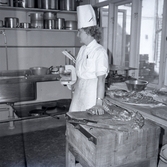 En kvinna i ett kök. På kuvert som medföljde bilden står det: Stadshotellet Englund.