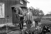 Man med häst framför hus, 1927