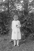 Konfirmand med psalmbok i trädgården 1920-tal