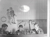 Tre unga guldsmeder visar sitt hantverk i guldsmed John Viktorins monter. Hantverksutställningen i Varberg 1927 i Gamlebyskolan, Varberg.