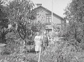 Birger och Adolfina Svensson i trädgården. Bilden tagen mot väster. Tomten låg i hörnet Träslövsvägen 5-Bryggaregatan, kv Vindragaren 15.