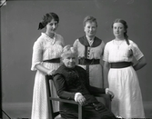 Ateljébild med fyra kvinnor i olika åldrar. Den äldsta sitter i en länsstol.