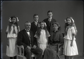 Ateljébild. Alfred Nilsson med familj, maka och fem barn där föräldrarna sitter. Två av döttrarna bär likadana sjömansklänningar och alla tre har utslaget hår med stora rosetter. Beställare: Alfred Nilsson. Fototid (osäker) 1910.