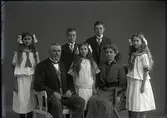 Ateljébild. Alfred Nilsson med familj, maka och fem barn där föräldrarna sitter. Två av döttrarna bär likadana sjömansklänningar och alla tre har utslaget hår med stora rosetter. Beställare: Alfred Nilsson. Fototid (osäker) 1910.
