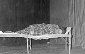Kvinna sover i säng på scen 1959