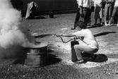 Deltagare använder bransläckare på kurs i brandförsvar, 1989
