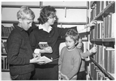 Bibliotekarie visar bok för unga besökare på biblioteksfilial i Markbackens skola, 1965
