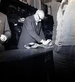 Grosshandlare Karl Danielsson bakom disken expedierar sina kunder tillsammans med Torsten Lundin dagen innan nyårsafton. Danielsson fyllde åttio år vid fototillfället.