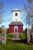 Kyrkan med smidesgrind i muren, från V   Roasjö