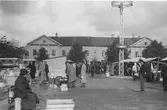 Torgmarknad år 1938 på Kungsbacka torg. På torgets mitt står en hög belysningsstolpe och till vänster i bild är bussparkeringen. I bakgrunden ses byggnaden i kv Tullen 8, kallad Gamla Gästis eller Medinska fastigheten, som var en av de första byggnaderna som uppfördes efter den stora branden i Kungsbacka 1846. Då var den ett av få tvåvåningshus i staden. Den 16 september 2006 ödelades det anrika huset i en ny brand.