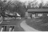 Lantgård i Förlanda med bostadshus och ekonomibyggnader. I förgrunden en mjölkpall, där mjölkbilen hämtade upp bondens mjölkkannor.