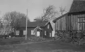 Lantgård invid Lindome kyrkby. Bostadshuset har en s k skunke kring dörren; en grund utbyggnad med rundat valv som sedavnligt har väggfasta bänkar längs sidorna. Till höger ses ett uthus på hög, kallmurad stenfot.