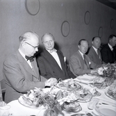Ruben Wagnsson till vänster och statsråd Eliasson, tredje från höger, vid ett dukat middagsbord.