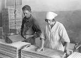 Kvinnan hadpressar gjutformarna för Läkerol. Mannen fyller formarna för hand, 1920-tal.