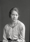 Kvinnoporträtt, sittande halvfigur. Flicka i småprickig blus med randig sjömanskrage. Beställare:  Agnes Sandell.