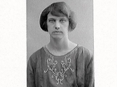 Kvinnoporträtt av Christina Berntsson från Tofta Lindberg. Klänningen har brodyr på bröstet.