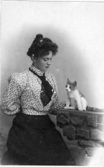 Ateljébild av en kvinna och en liten katt som sitter på rekvisitamuren.