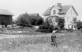 Äldre dam framför Svenssons gård i Bettorp i Hovsta, 1930-tal