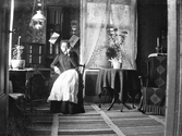 Botolfina Andersson sitter vid telefonväxeln i sitt hem i Slöinge. Hon skötte telefonstationen i Slöinge fram till sin död 1913, därefter tog hennes syster Armida över arbetet. Botolfina var född i Galtabergen i Getinge.